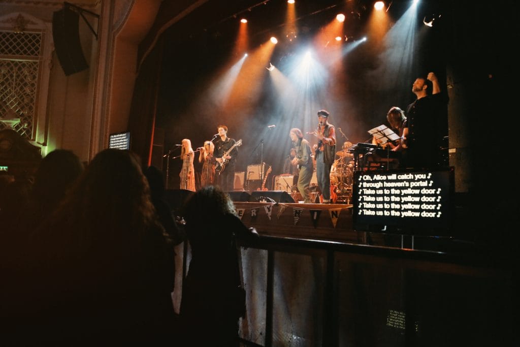 This is an image of a live music gig which also has a screen for captioning.